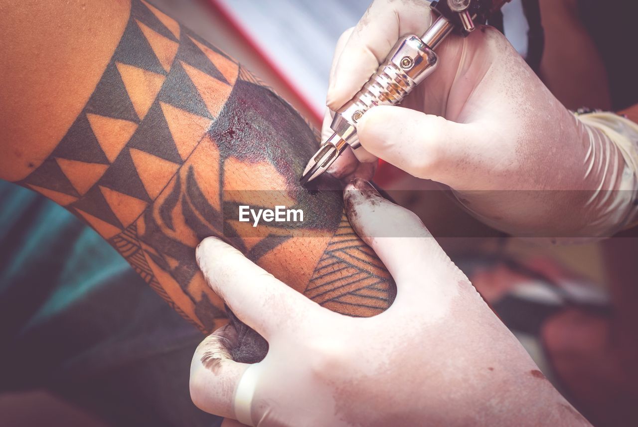 Cropped hand making tattoo on man