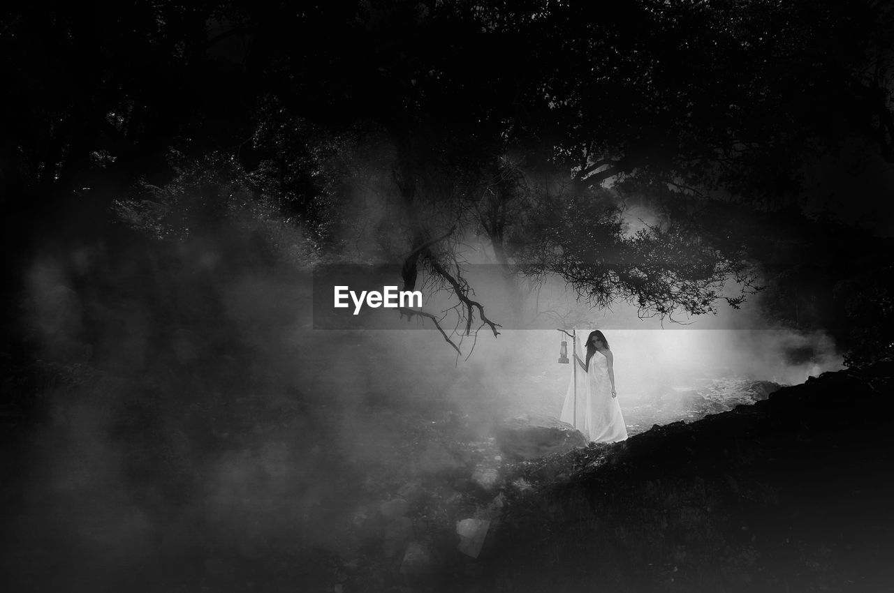 Woman standing in forest during foggy weather