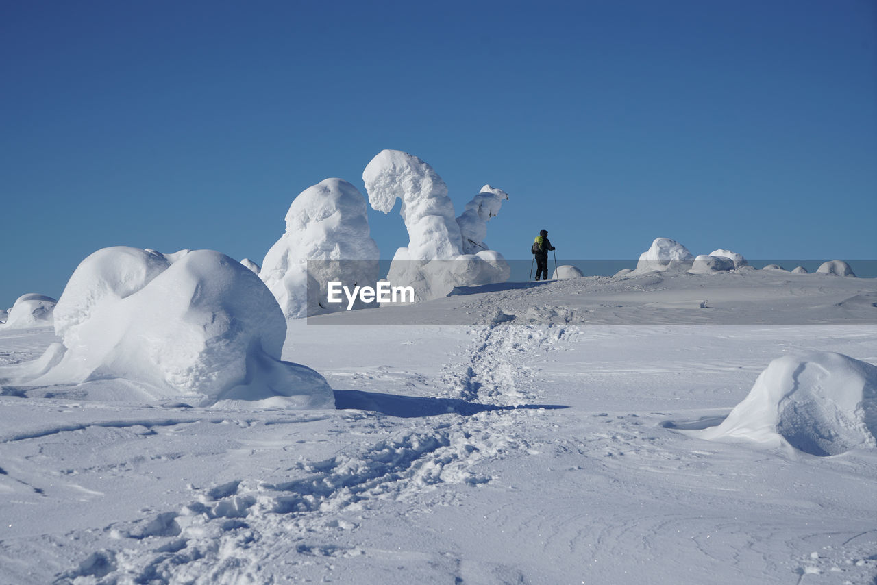 Person on snowcapped mountain against clear blue sky
