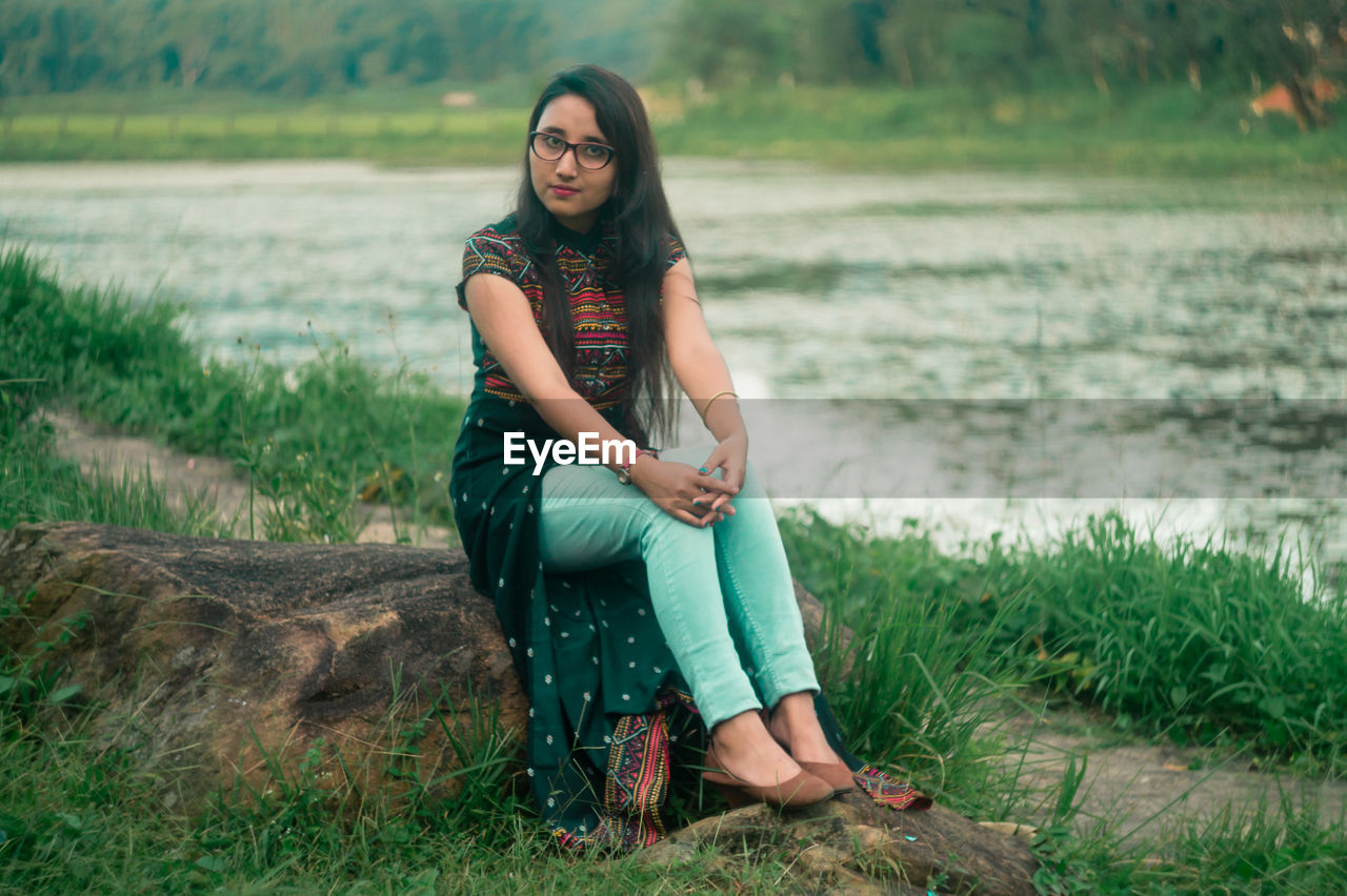 Portrait of young woman sitting on rock