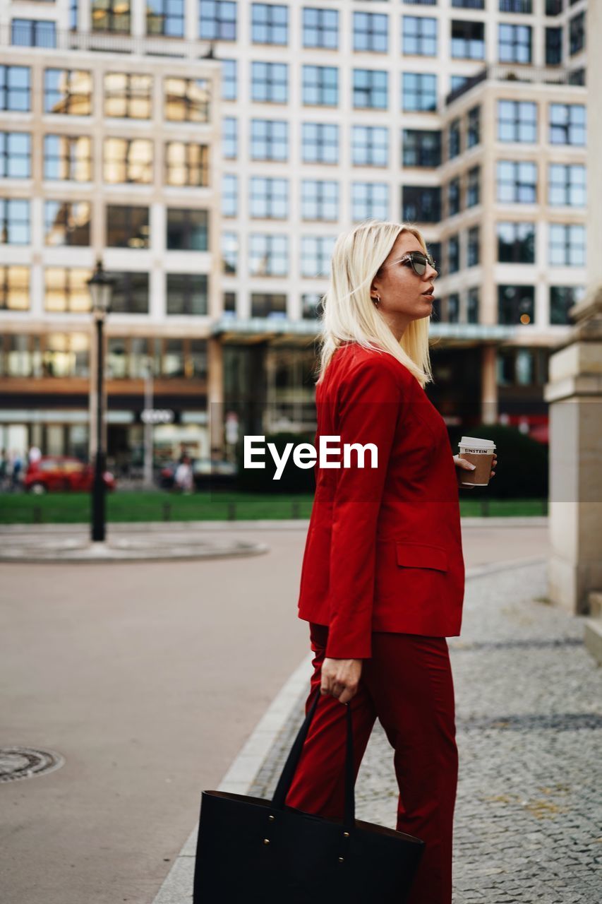 Side view of woman wearing red suit walking on street