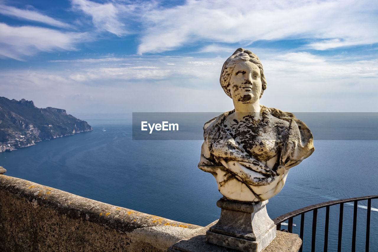 STATUE BY RAILING AGAINST SEA AND SKY