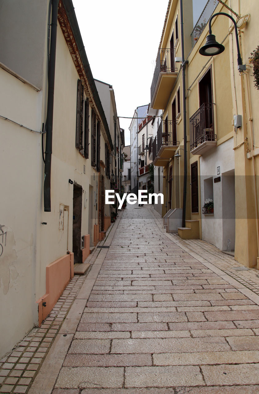 architecture, building exterior, alley, built structure, road, street, town, building, city, the way forward, cobblestone, neighbourhood, residential district, lane, footpath, diminishing perspective, sky, house, nature, day, no people, outdoors, narrow, road surface, infrastructure, travel destinations, residential area, clear sky, vanishing point, wall