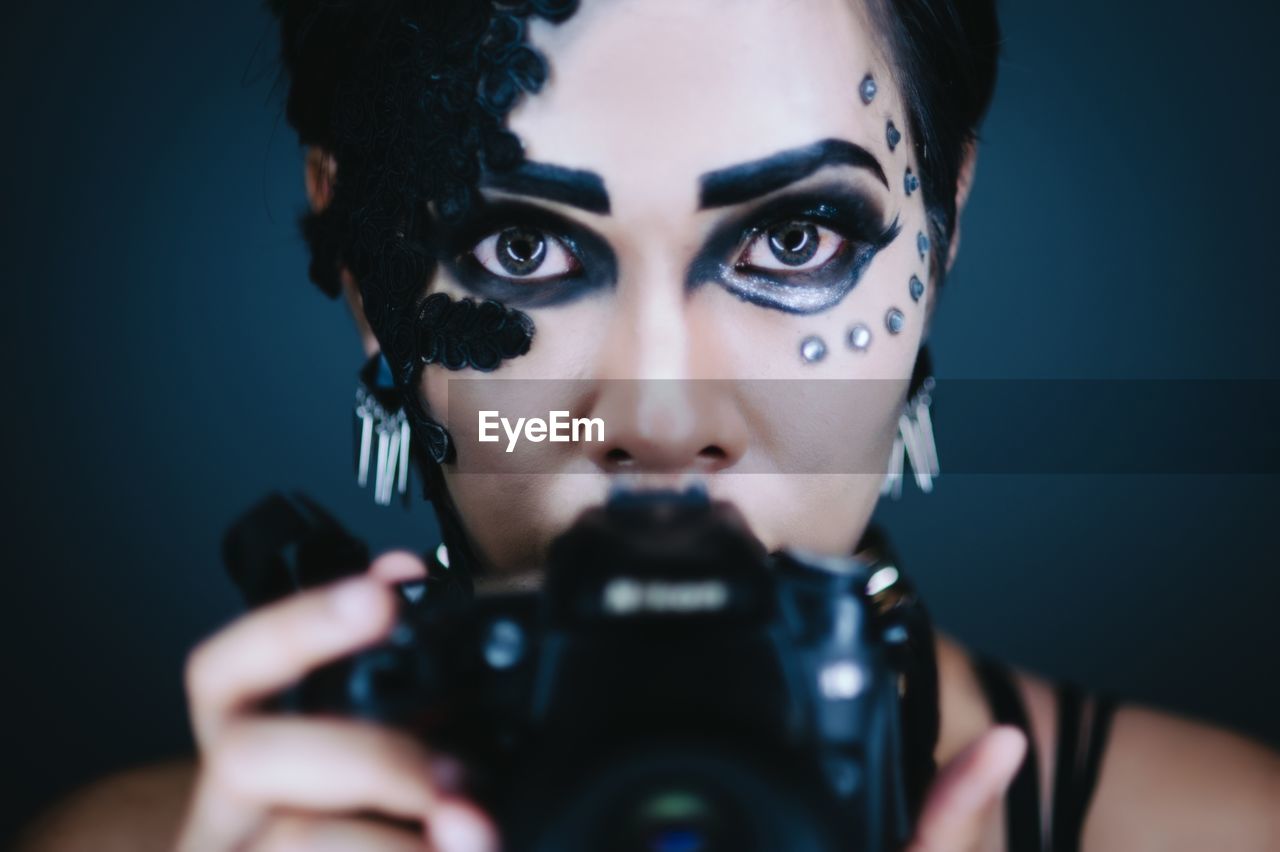 CLOSE-UP OF WOMAN HOLDING CAMERA