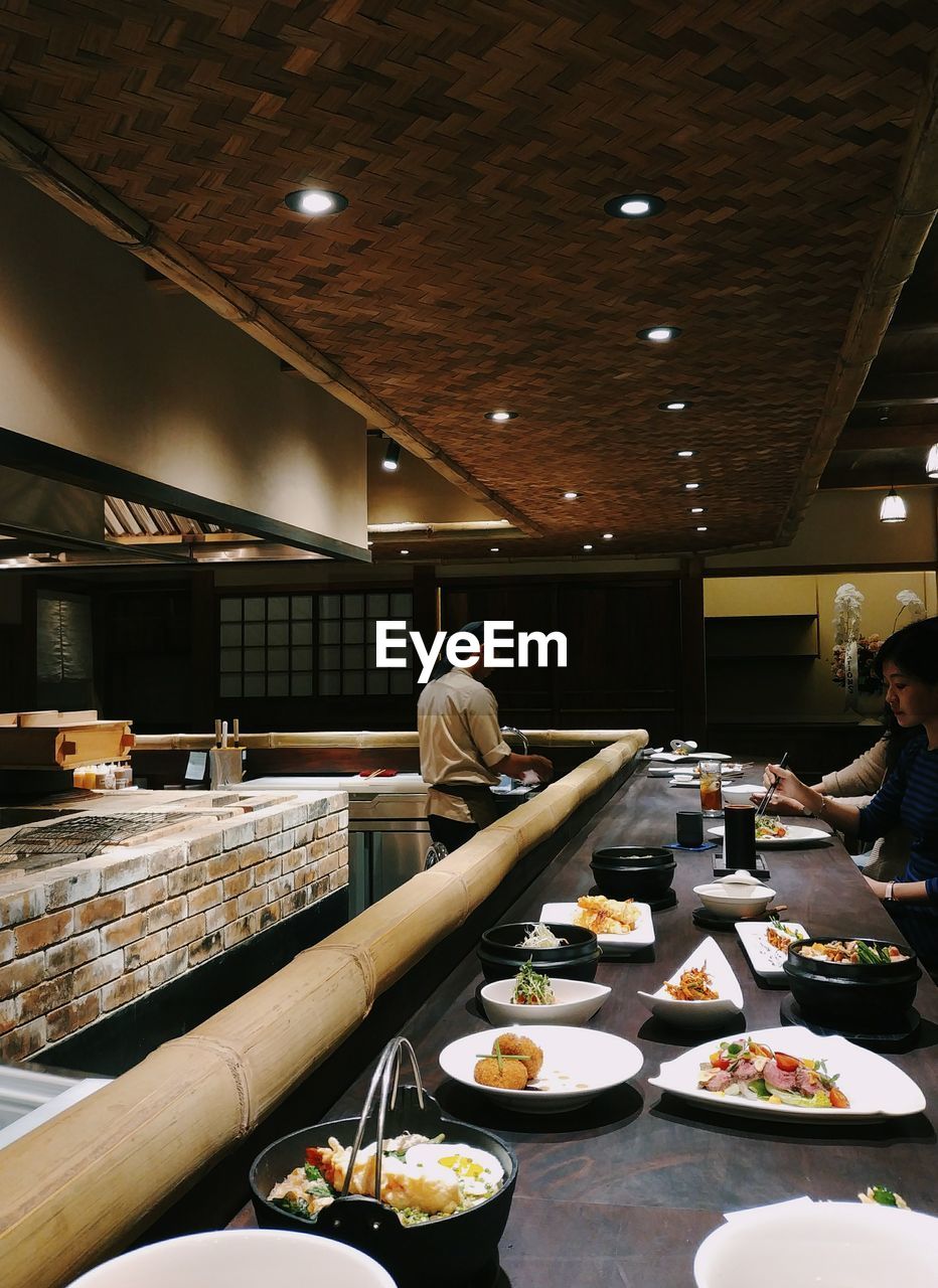 PEOPLE STANDING BY ILLUMINATED RESTAURANT