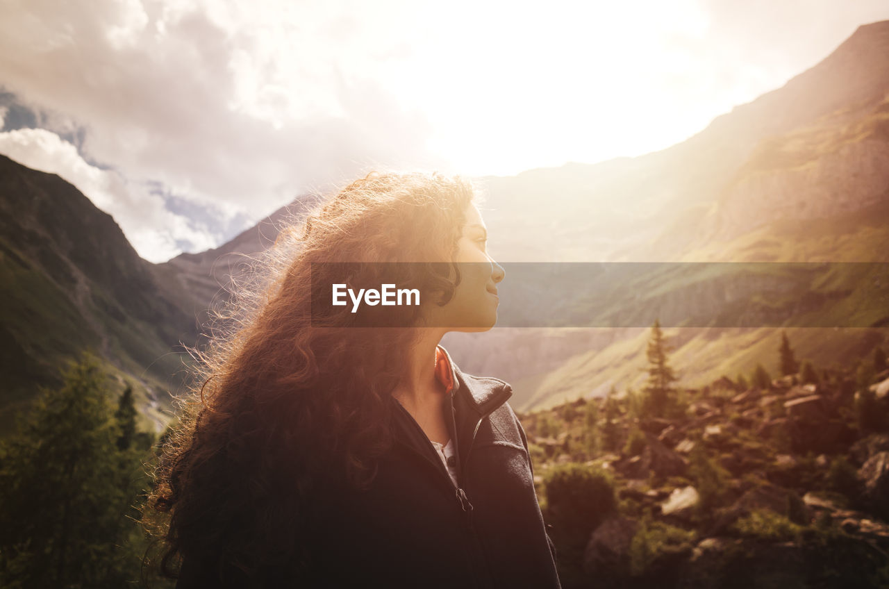 Young woman standing against mountains