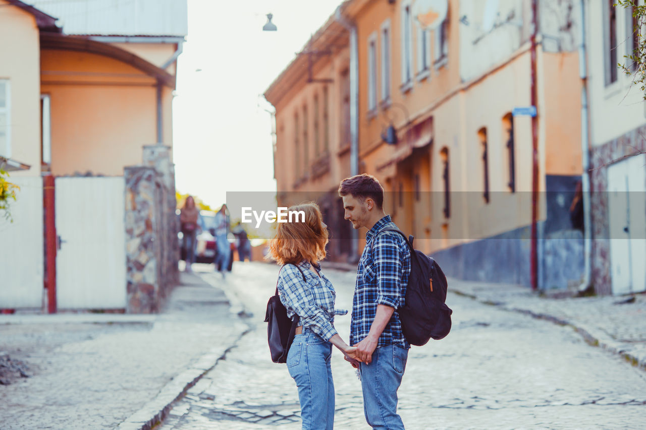 Rear view of friends standing on street in city