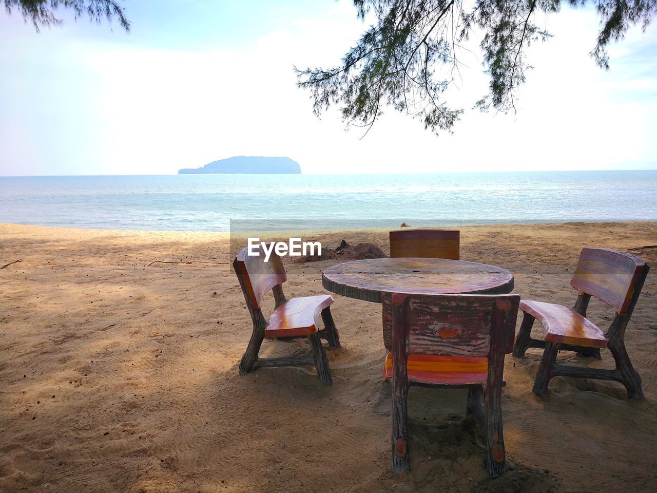 CHAIRS AND TABLES ON BEACH AGAINST SKY