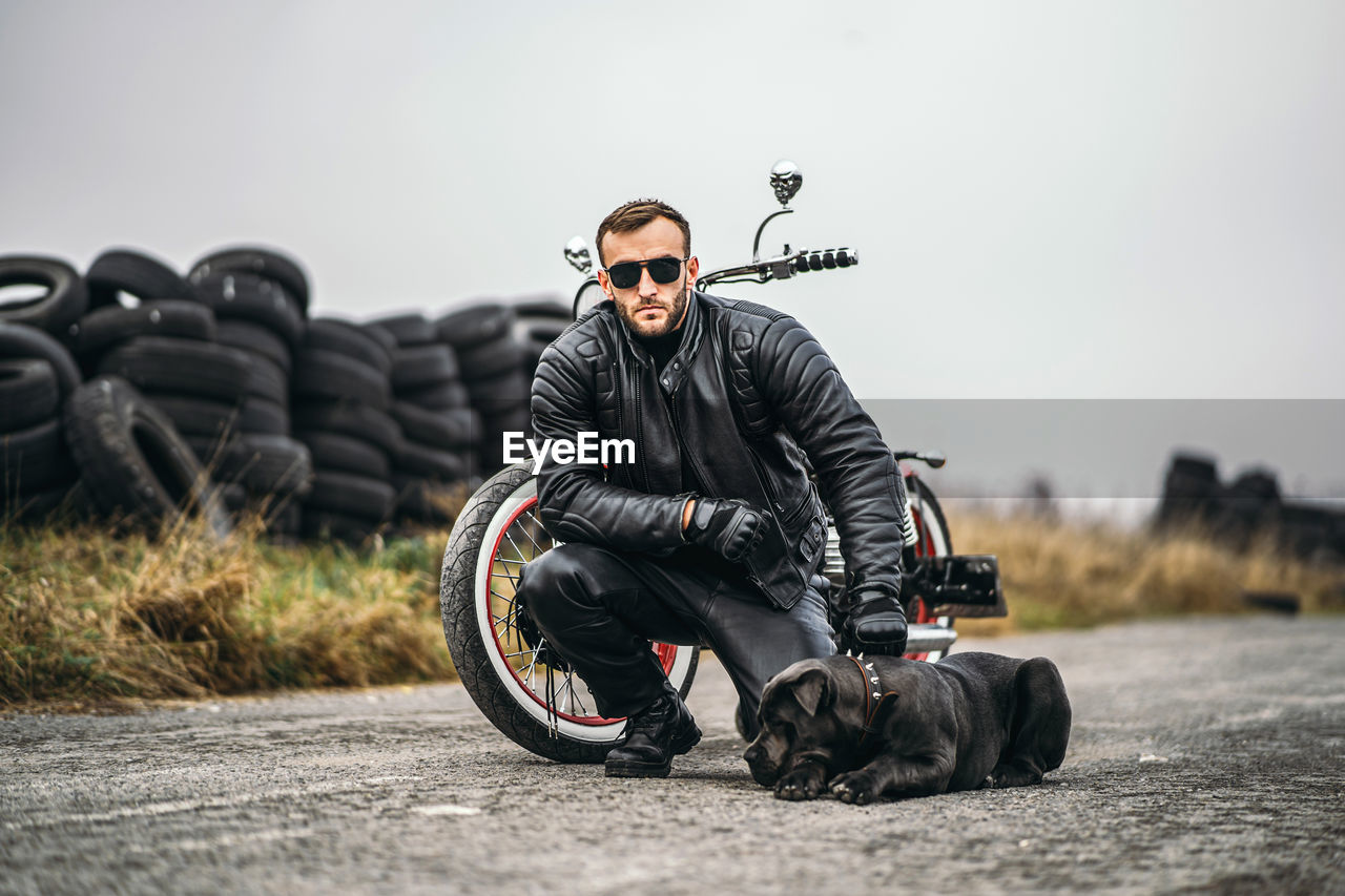 Young man sitting near bike on road