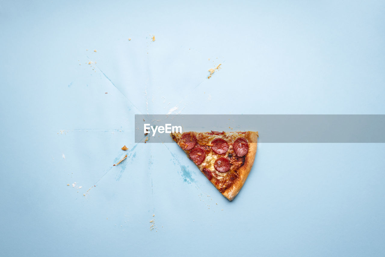 Directly above shot of pizza slice on blue background