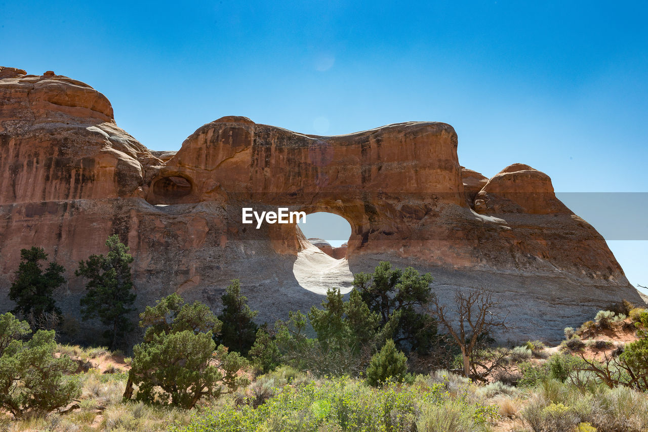 Rock formation on field against blue sky