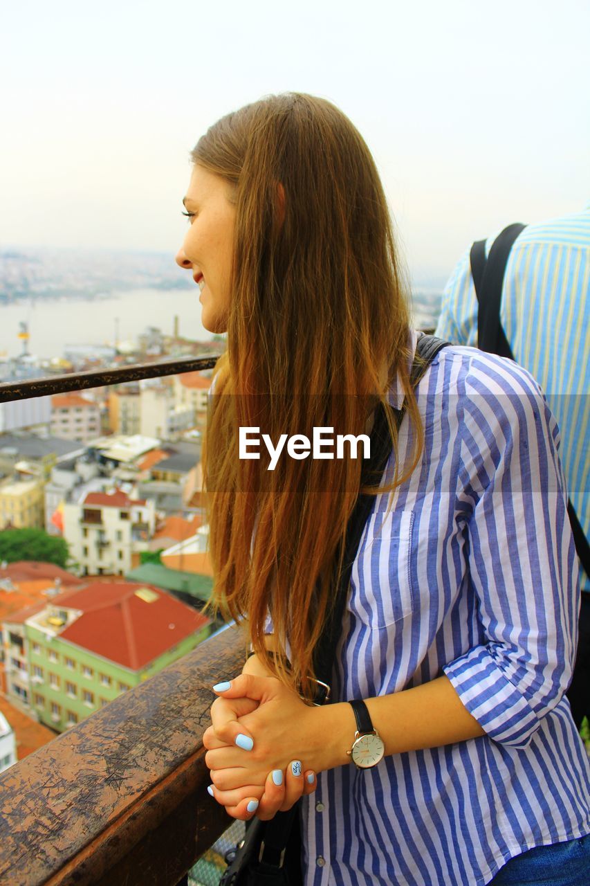 Young woman looking away while standing by railing