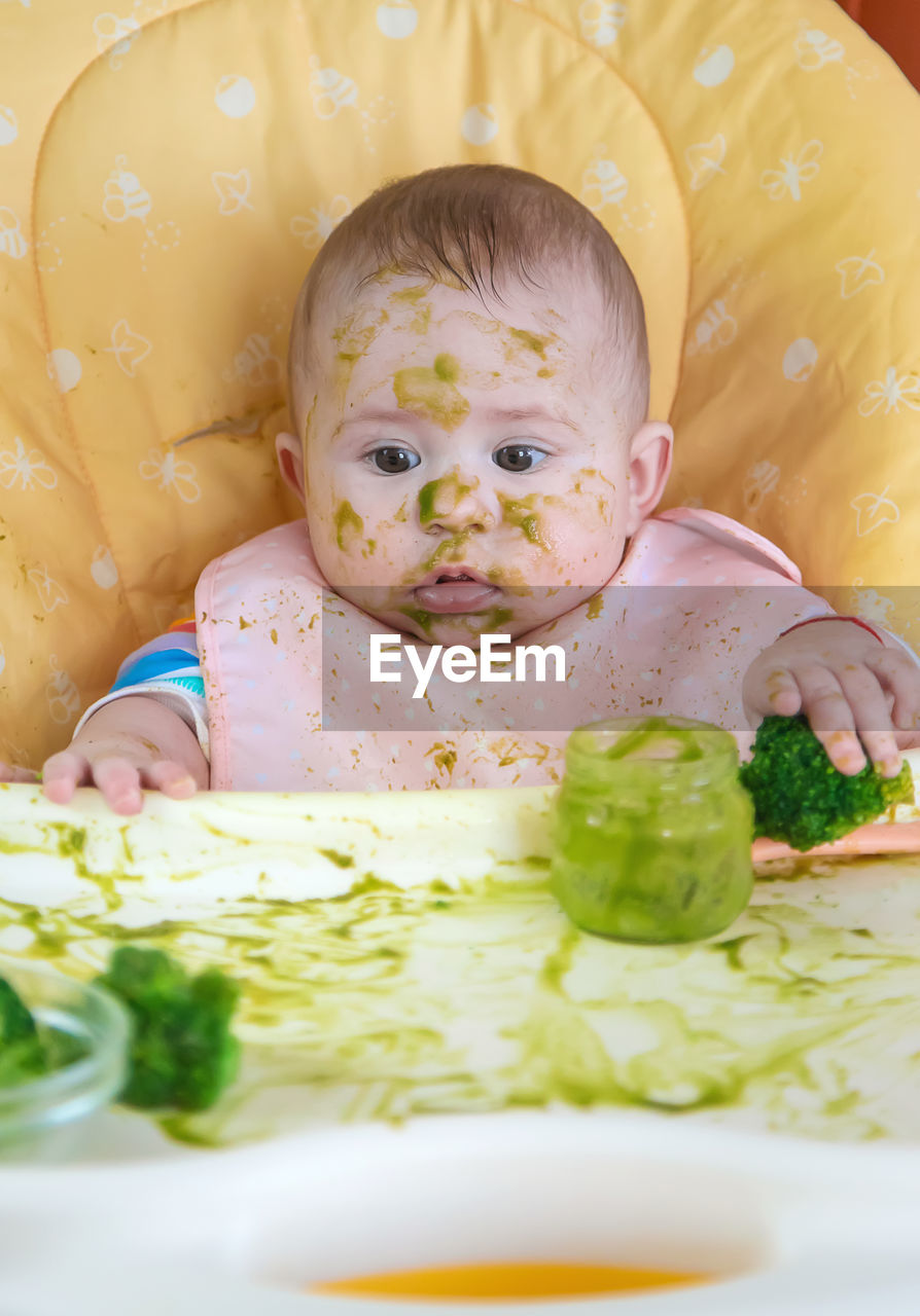 high angle view of cute baby girl eating food on table