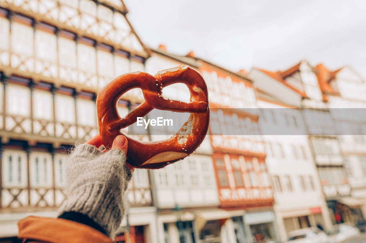 A girl holding a traditional german pretzel on the background of a beautiful architecture 
