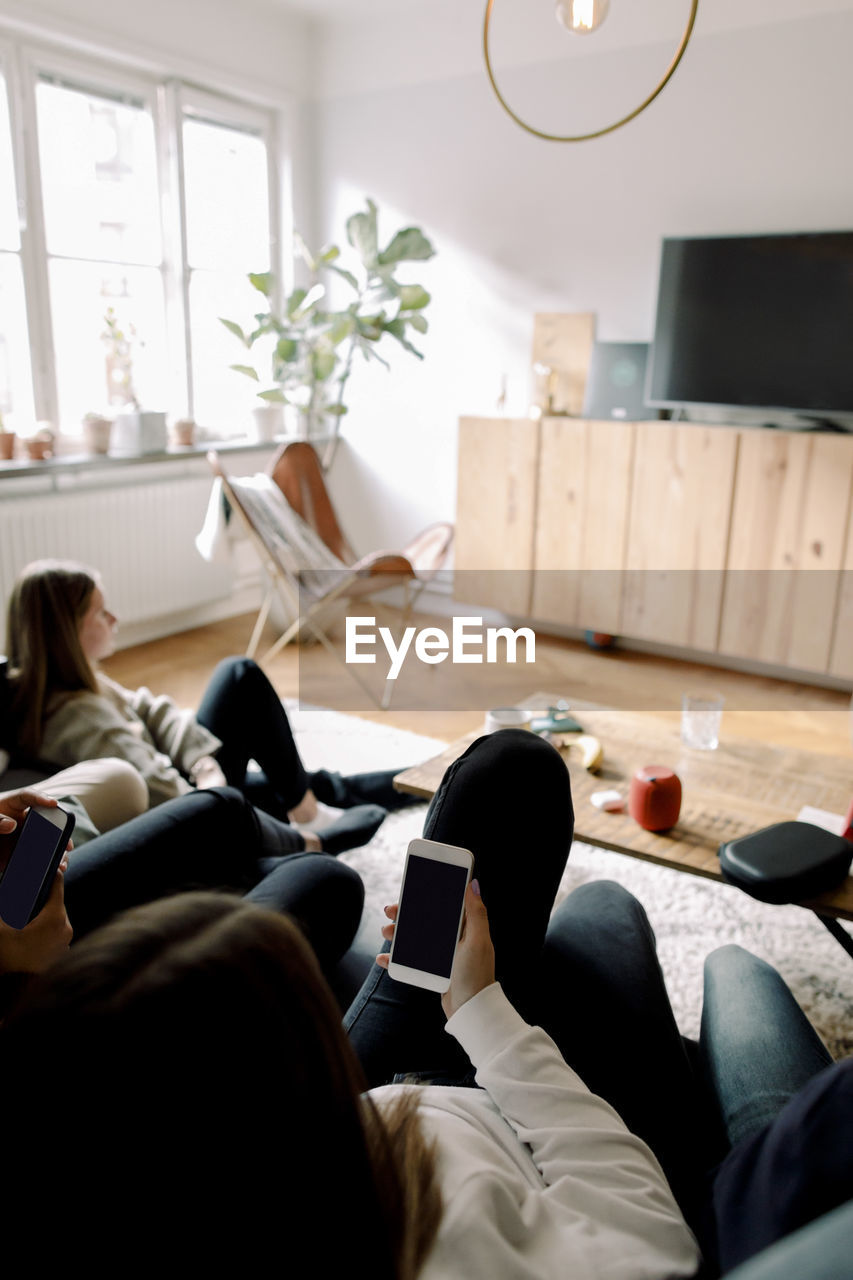 Teenagers using mobile phones while relaxing at home