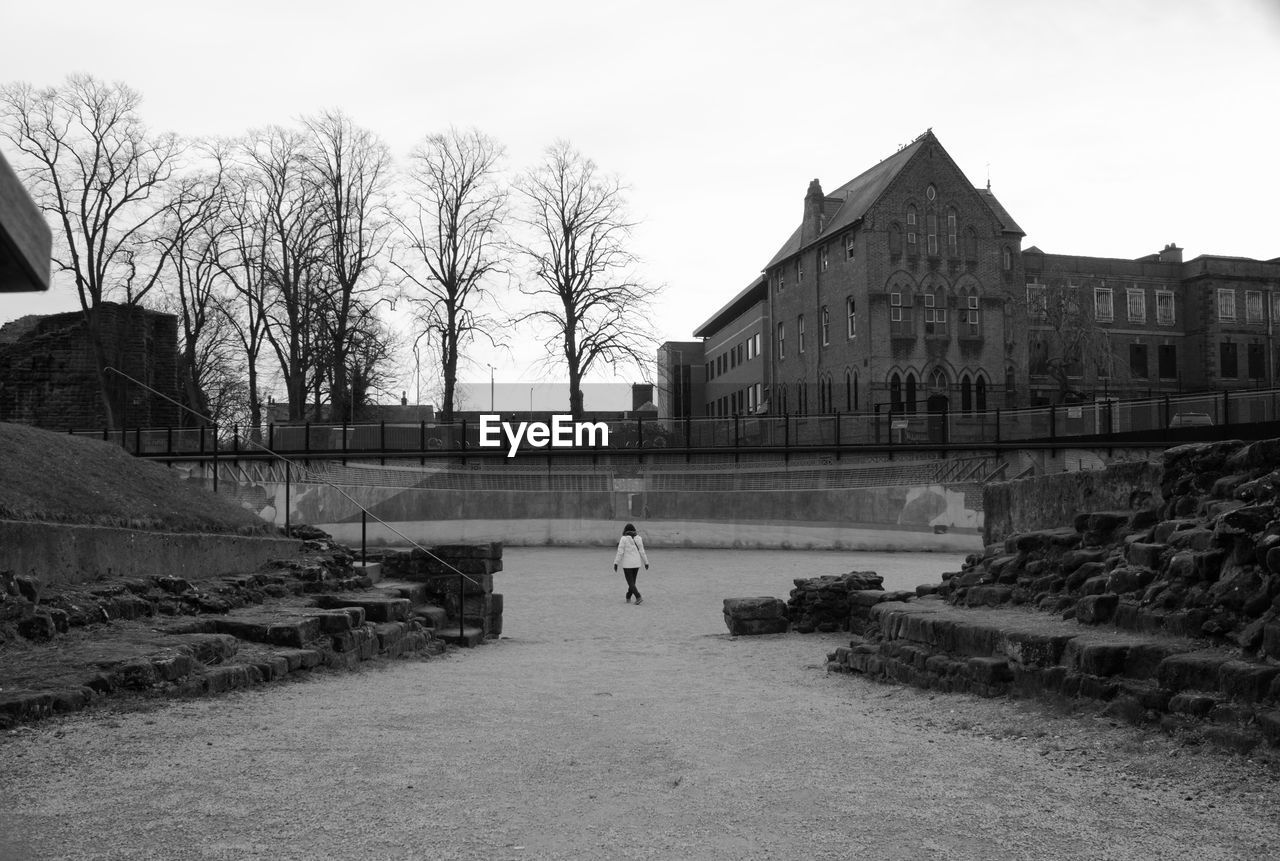 REAR VIEW OF WOMAN WITH BUILDING IN BACKGROUND