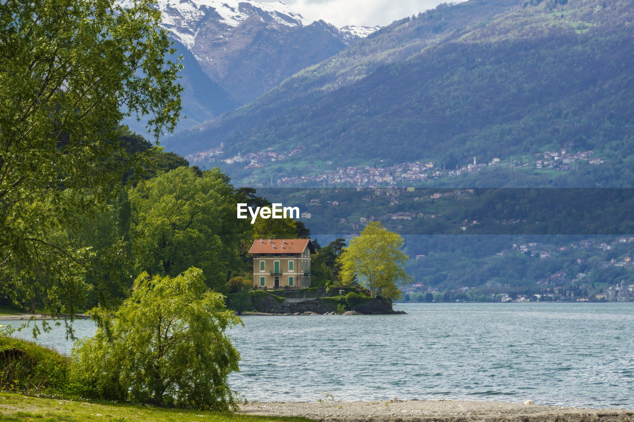 mountain, water, scenics - nature, plant, architecture, tree, beauty in nature, nature, built structure, building, environment, landscape, land, mountain range, building exterior, lake, sky, house, no people, travel destinations, tranquility, travel, tranquil scene, outdoors, day, tourism, green, grass, residential district, rural scene, idyllic, village, snow, non-urban scene, forest, beach, cloud, summer, vacation
