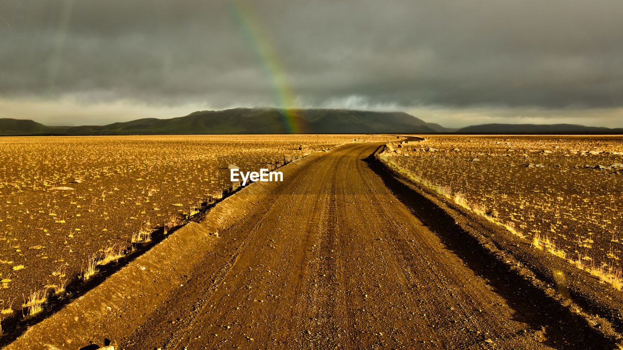 Road amidst field against sky