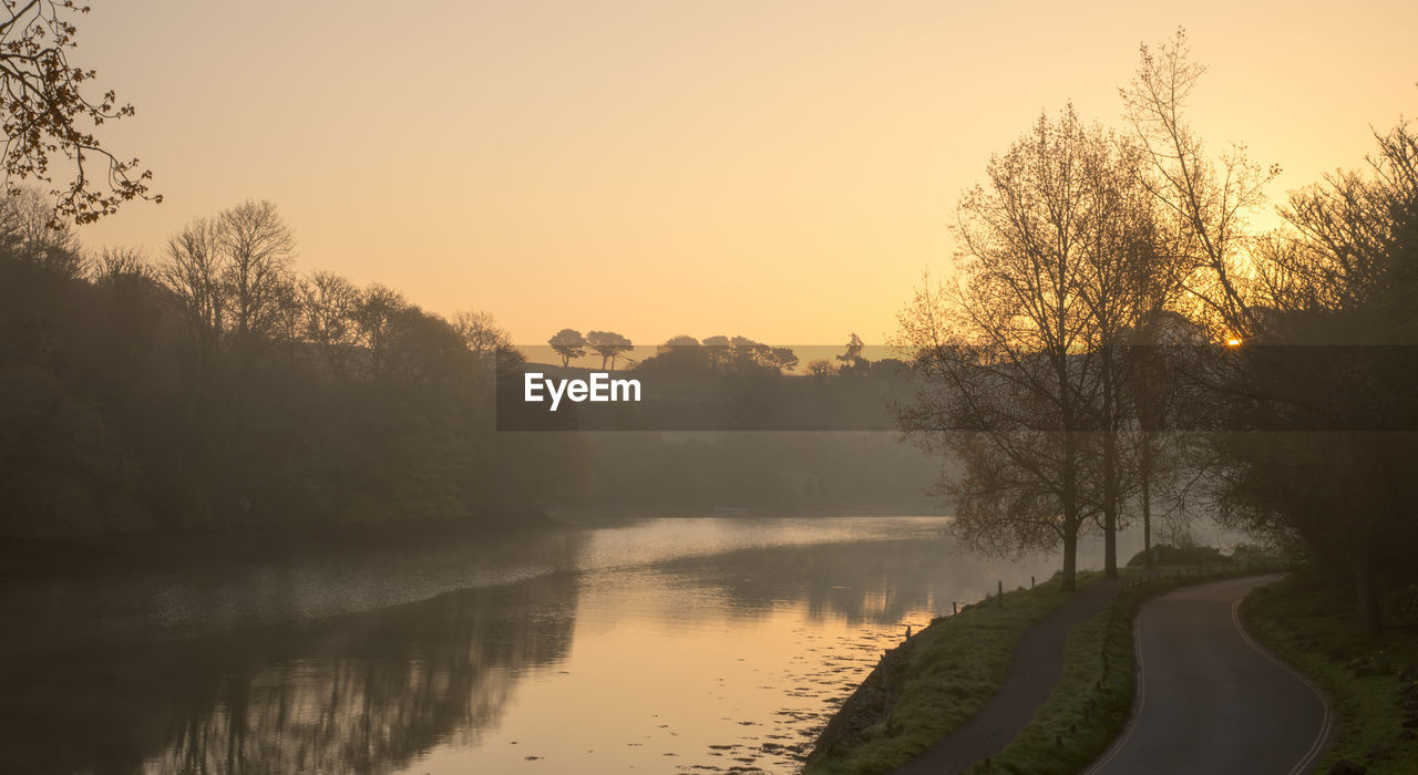 Scenic view of river against sky at sunset