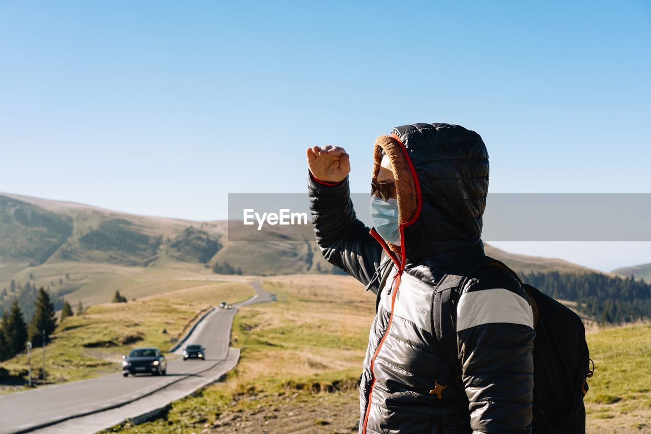 Side view of man with mask standing on mountain road