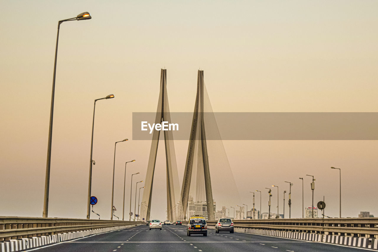 Cars on bridge against sky in city