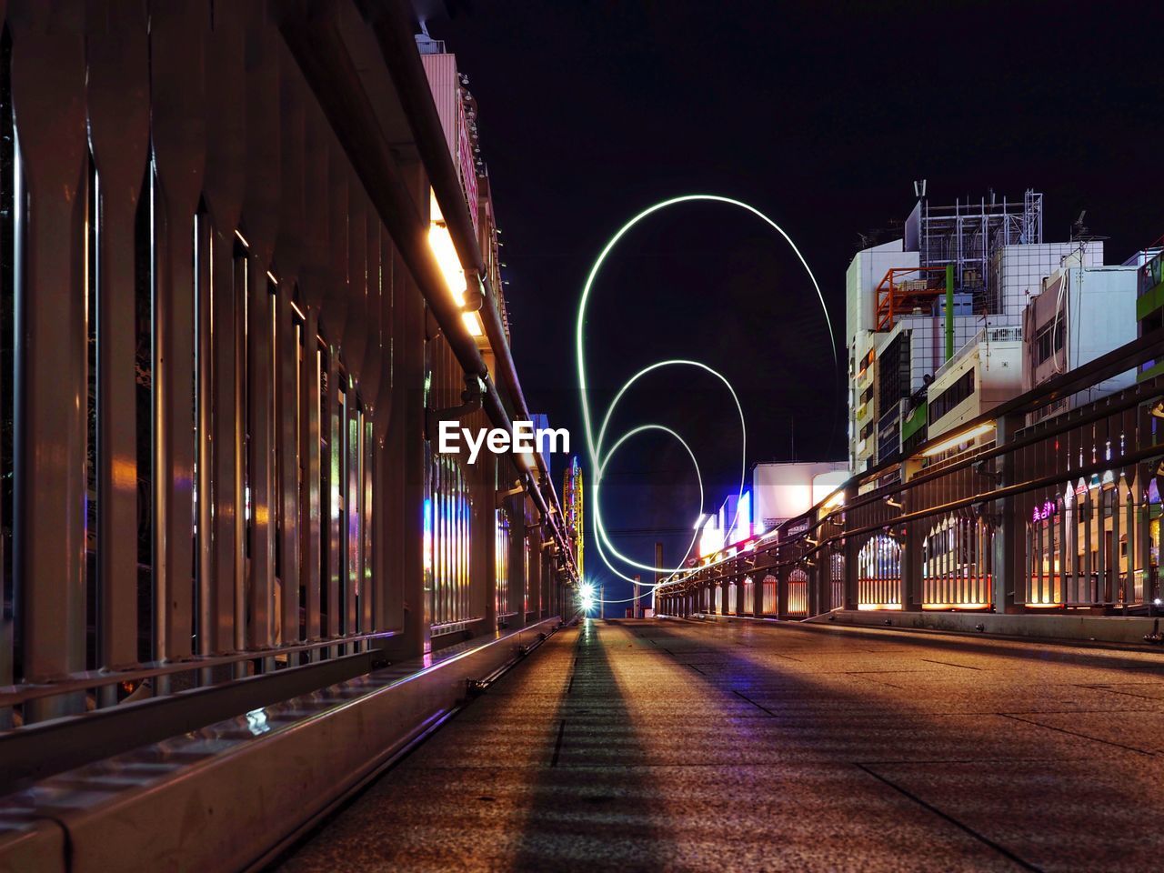 Illuminated light trails on road amidst buildings in city at night