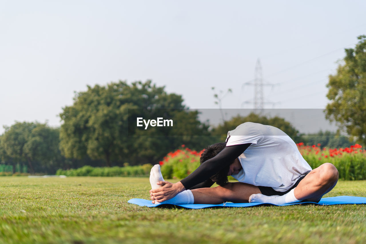 full length of young woman exercising on field