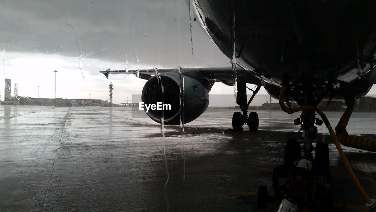 Airplane in rain viewed through wet glass window