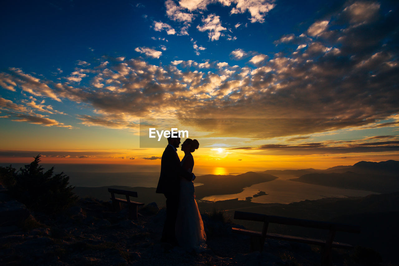 COUPLE STANDING AT SUNSET