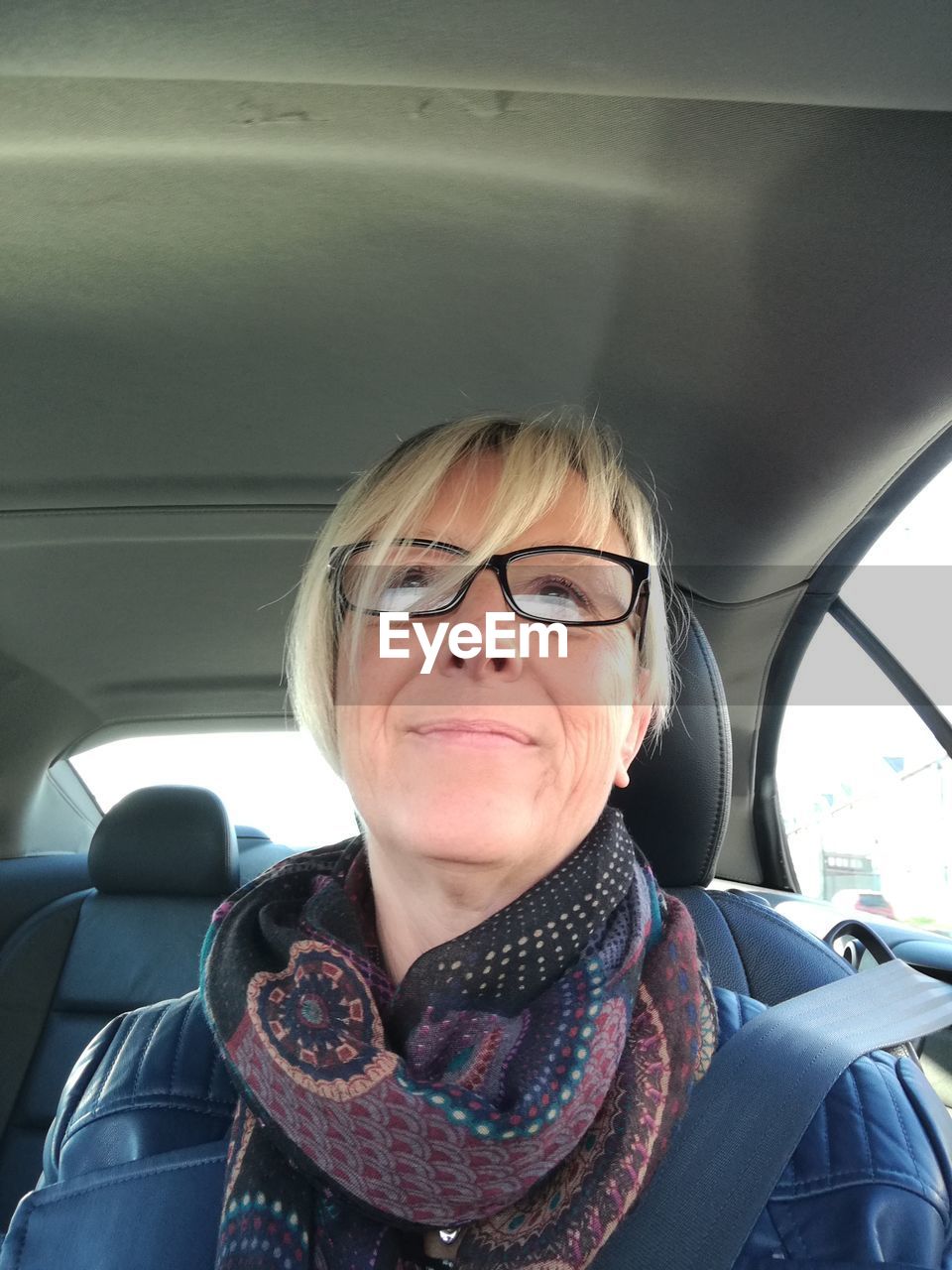 Thoughtful senior woman sitting on car