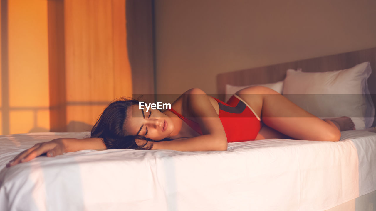 Tired beautiful young woman falling asleep in bed after relaxing day at pool