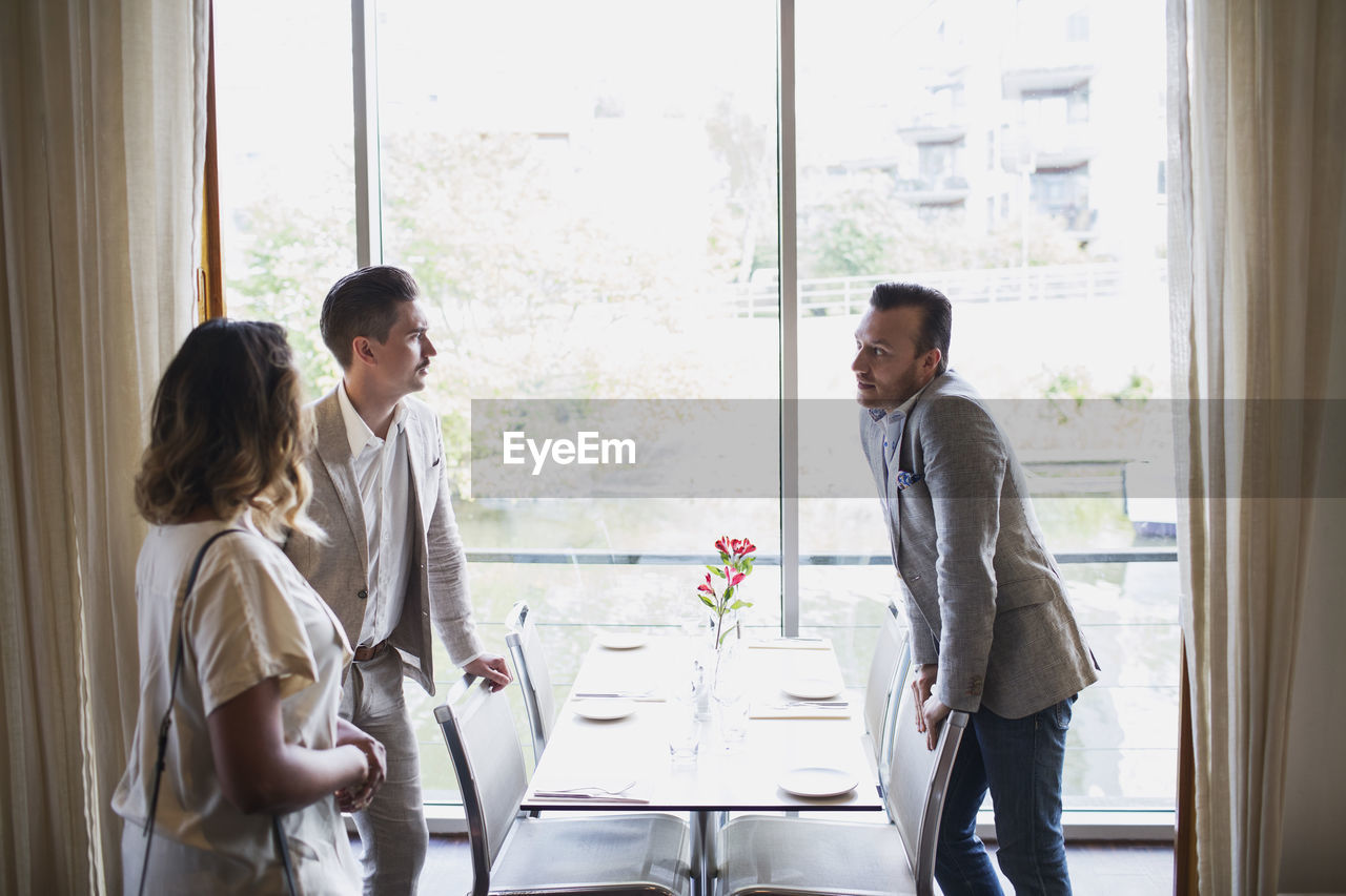 Business people standing by table against window at restaurant