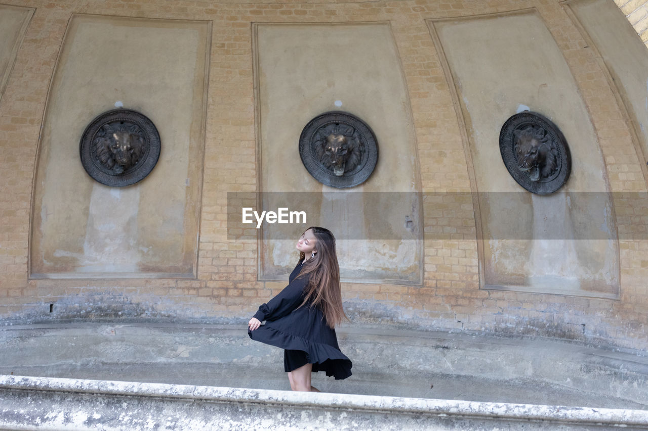 Full length of woman standing against building