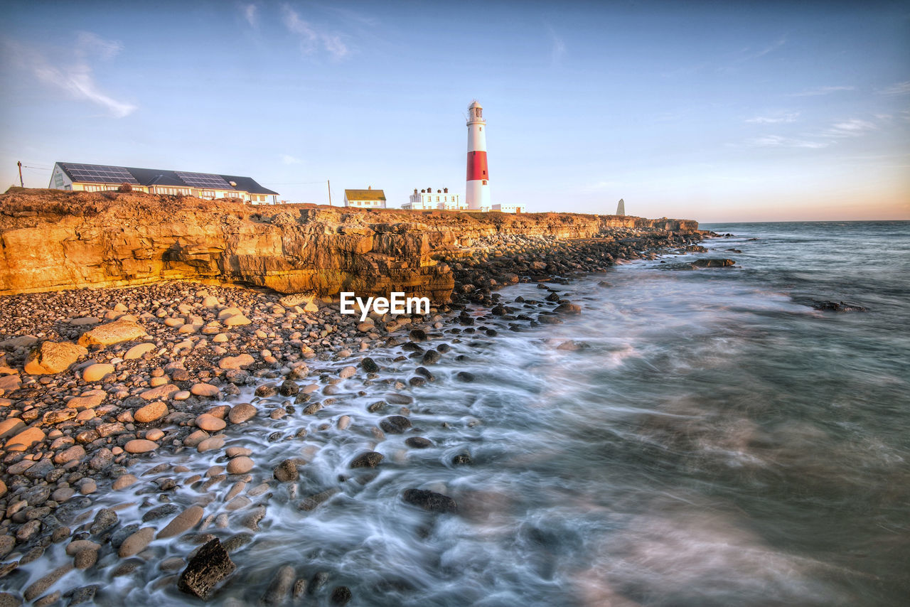LIGHTHOUSE ON ROCKS AGAINST SKY