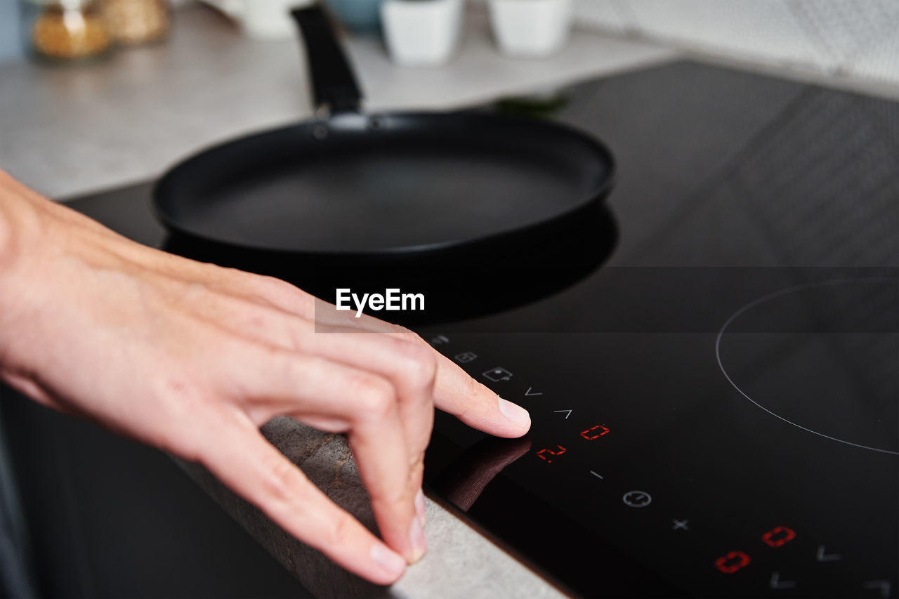 Woman hand turns on modern induction stove in the kitchen