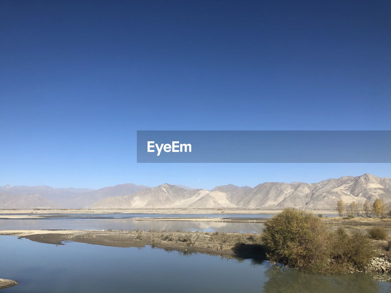 SCENIC VIEW OF LAKE BY MOUNTAINS AGAINST CLEAR BLUE SKY