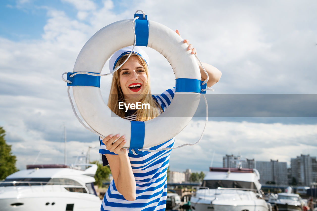 Young woman standing on yacht posing with lifebuoy