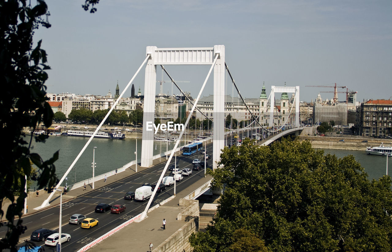 HIGH ANGLE VIEW OF SUSPENSION BRIDGE IN CITY AGAINST SKY