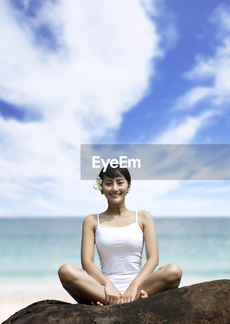 Portrait of woman sitting against sea and sky