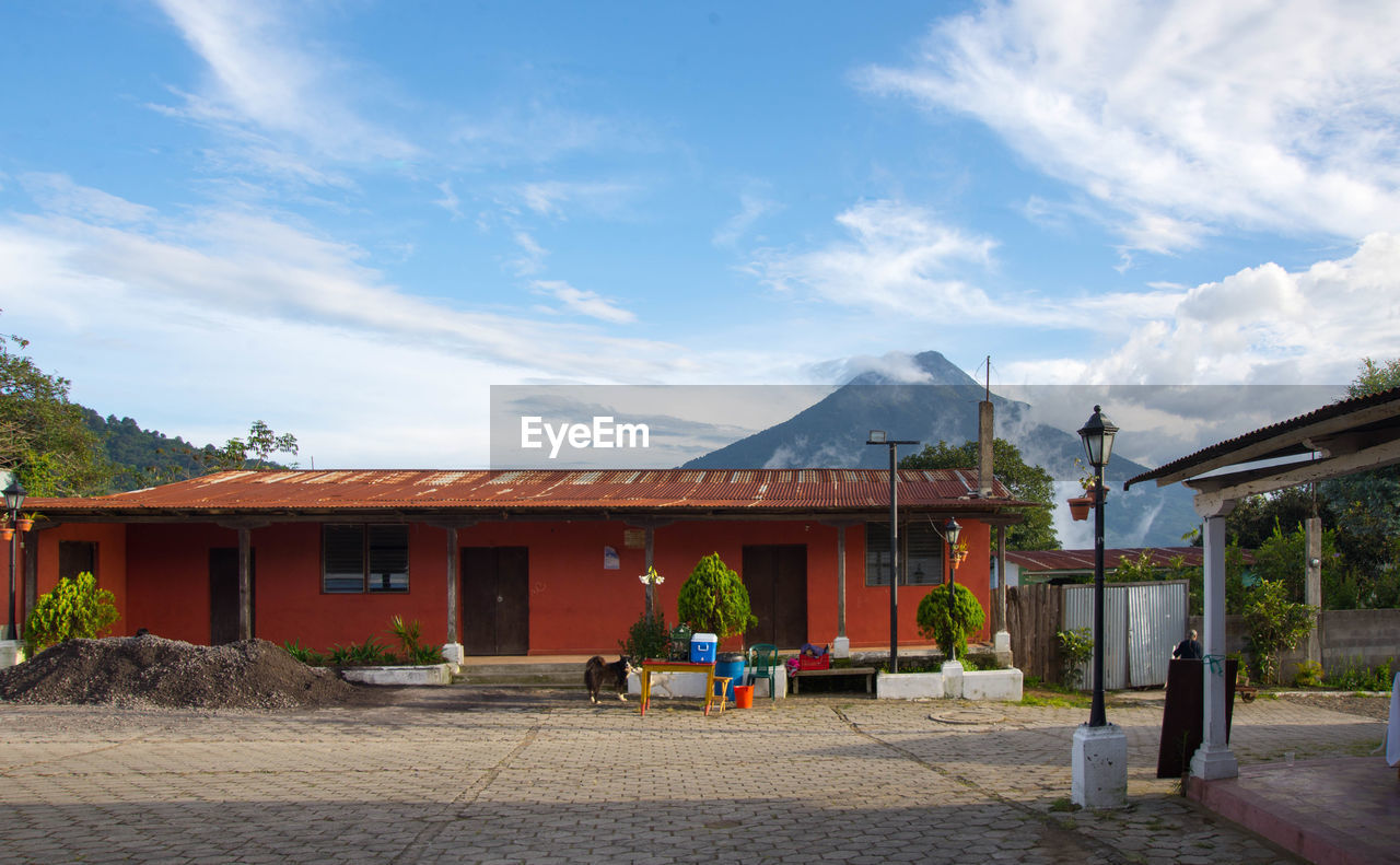 Building by mountain against cloudy sky
