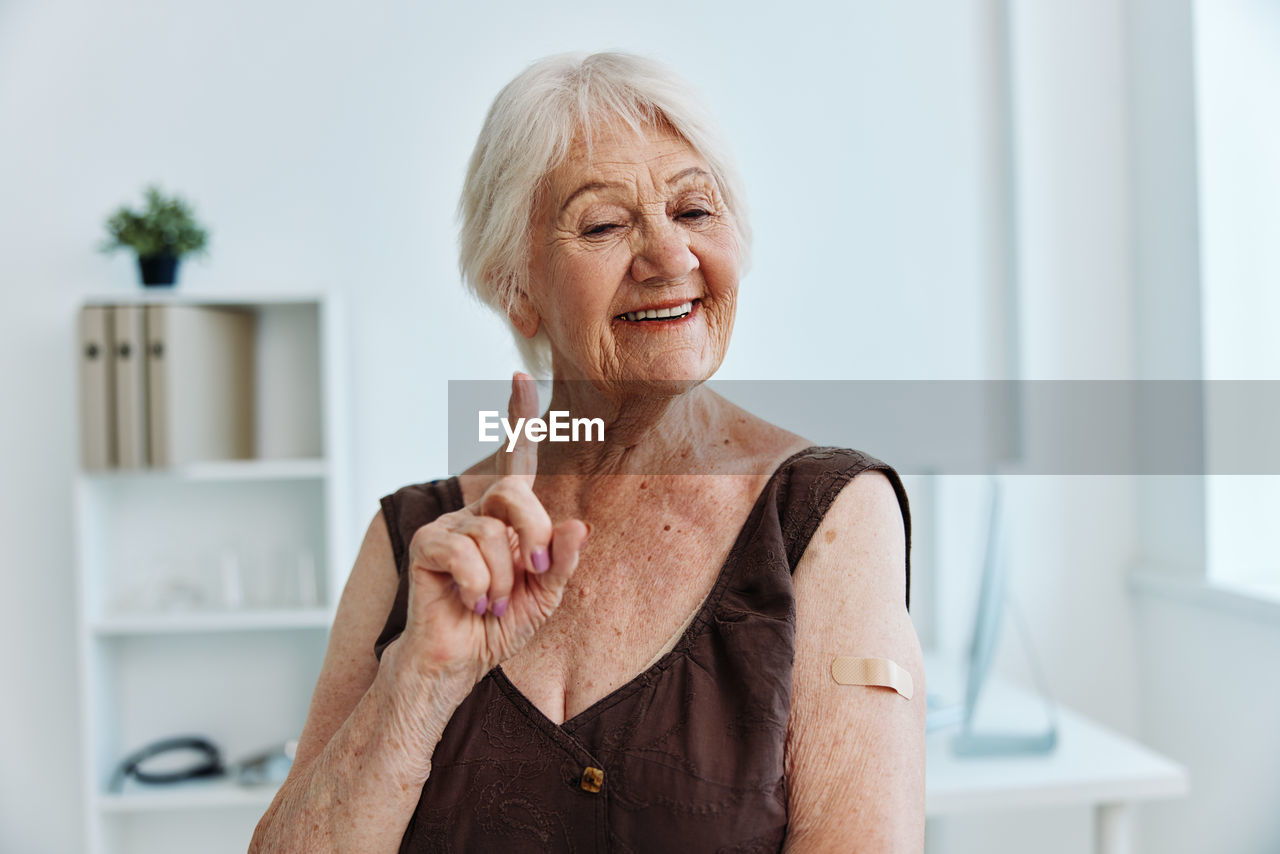 Smiling senior woman gesturing at hospital