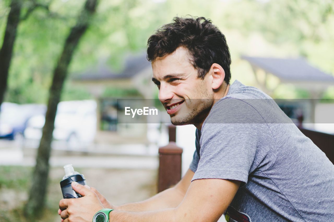 Side view of smiling young man looking away