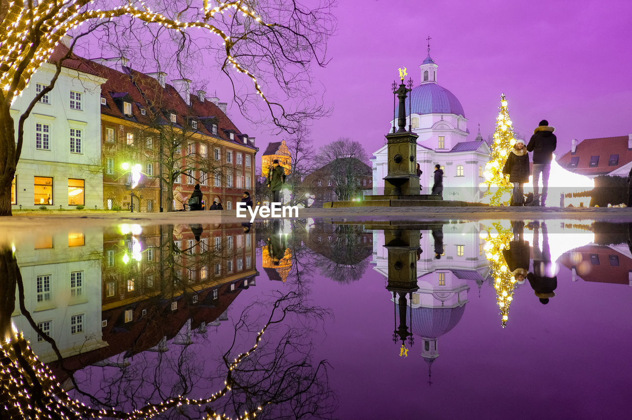 Reflection of buildings on puddle at night