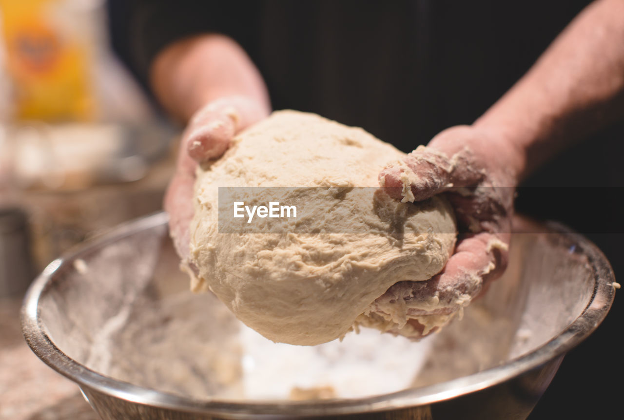 Midsection of man kneading dough