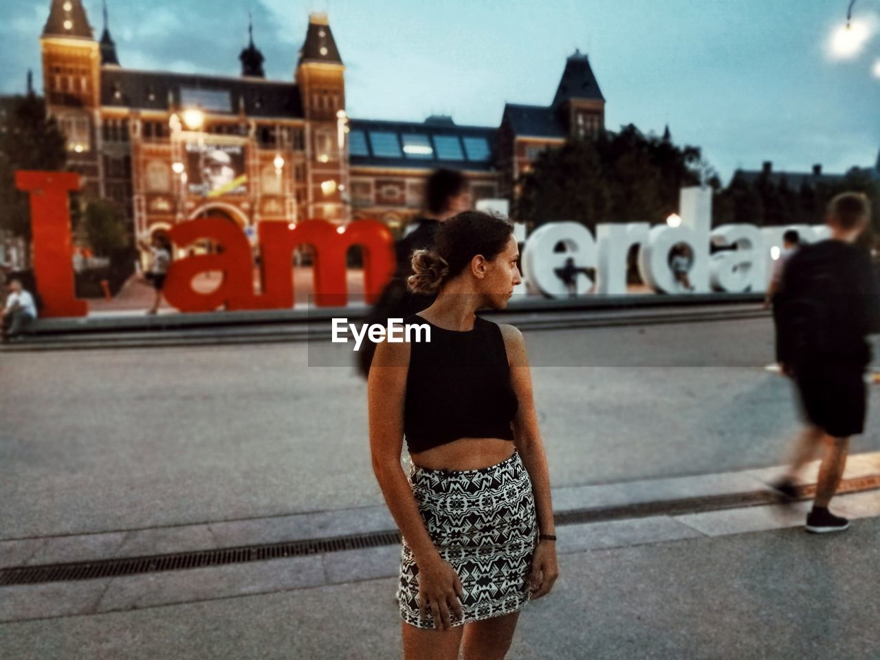 Woman looking over shoulder while standing on street in city