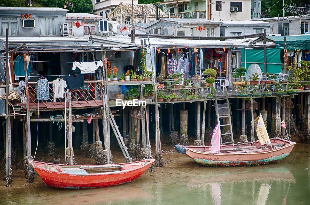 Boats moored on riverbank against stilt houses