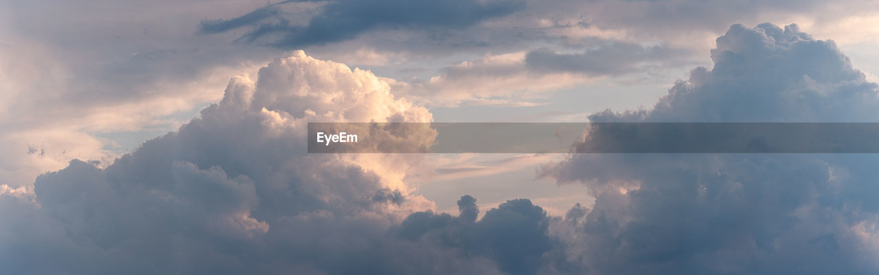 LOW ANGLE VIEW OF SUN STREAMING THROUGH CLOUDS DURING SUNSET