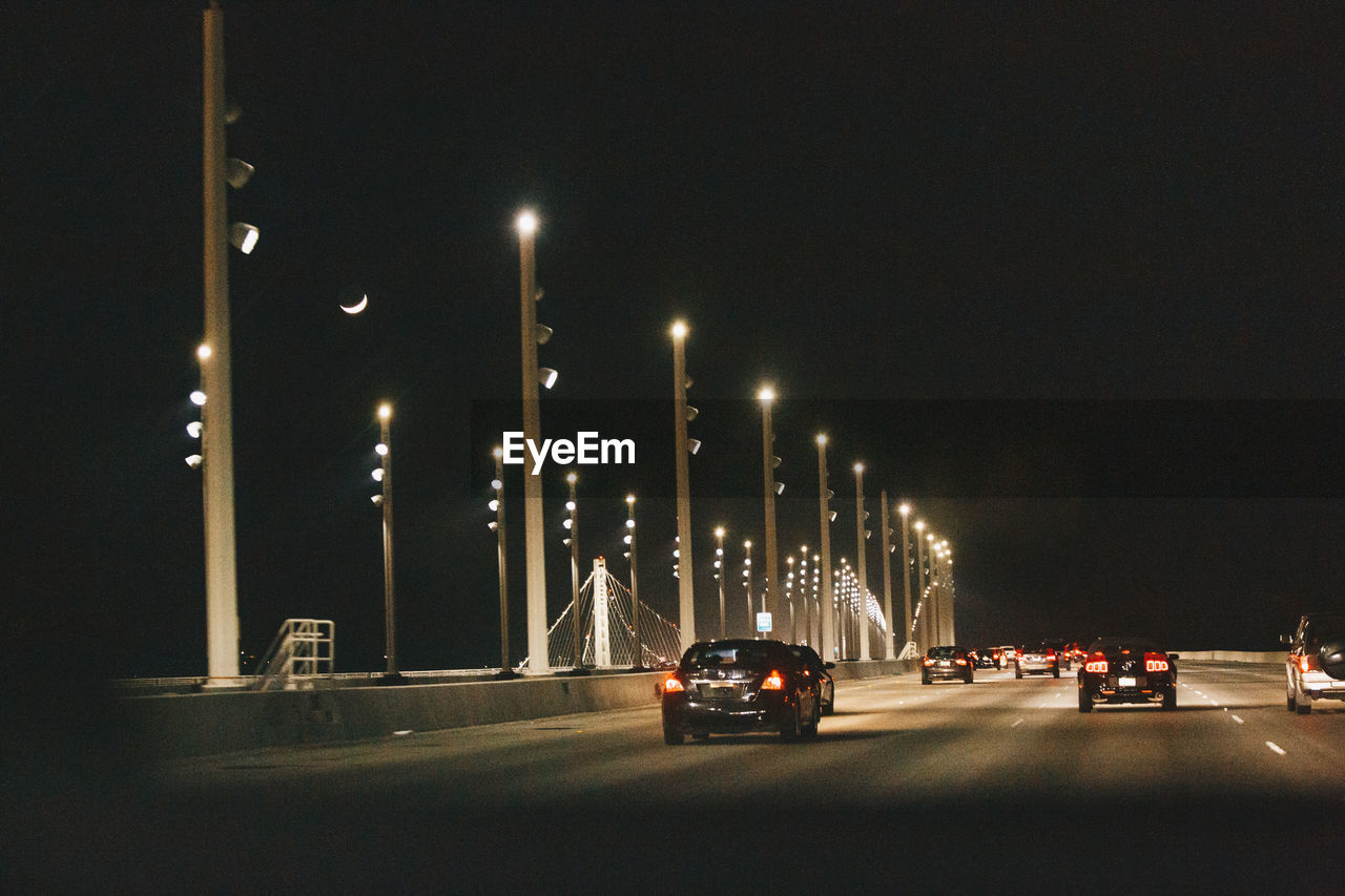 VEHICLES ON ROAD AGAINST SKY AT NIGHT