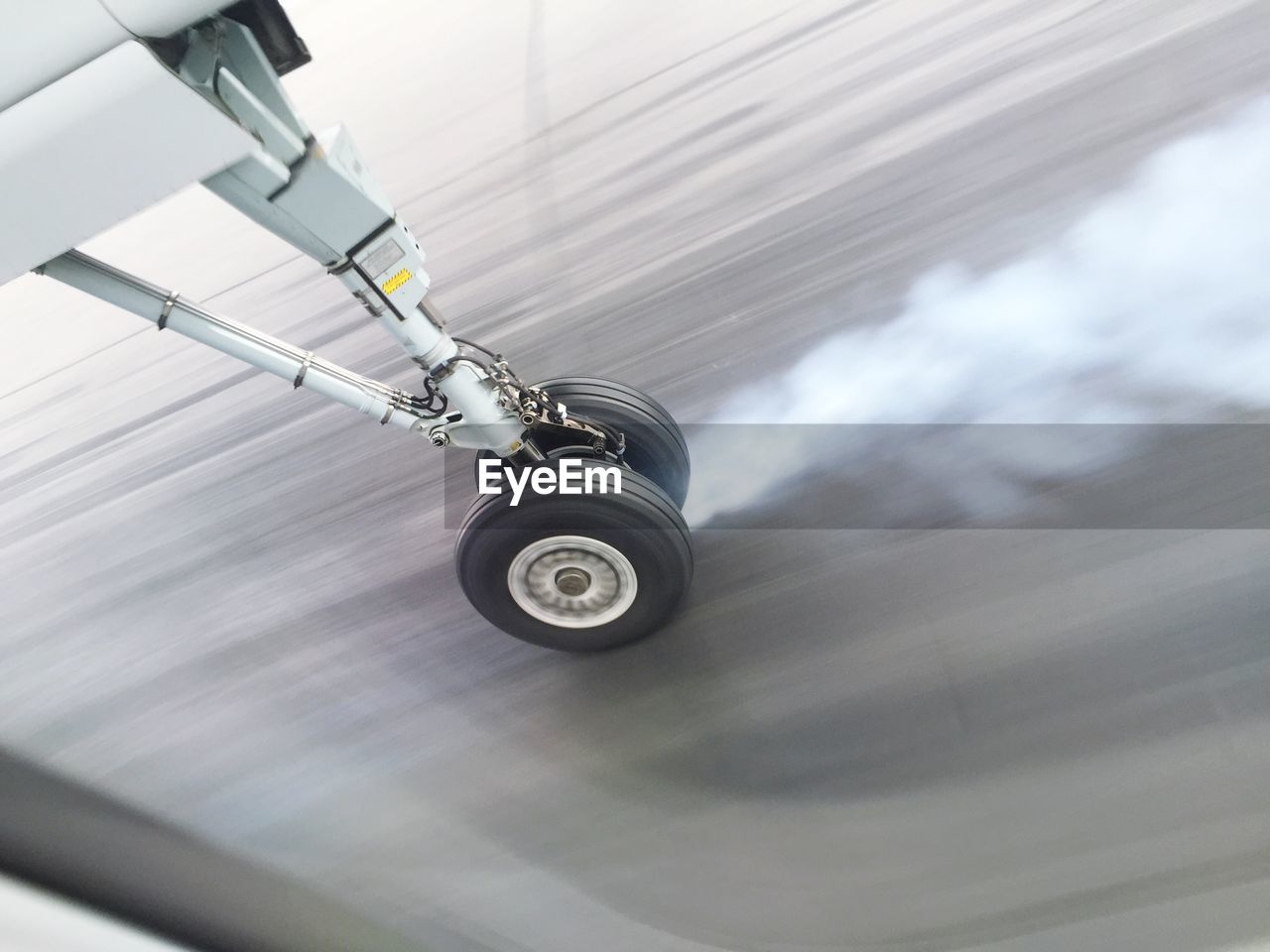 High angle view of smoke emitting from airplane wheel while landing on runway