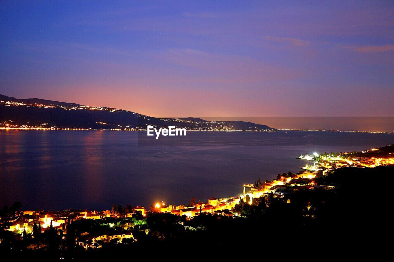 ILLUMINATED CITY BY SEA AT NIGHT